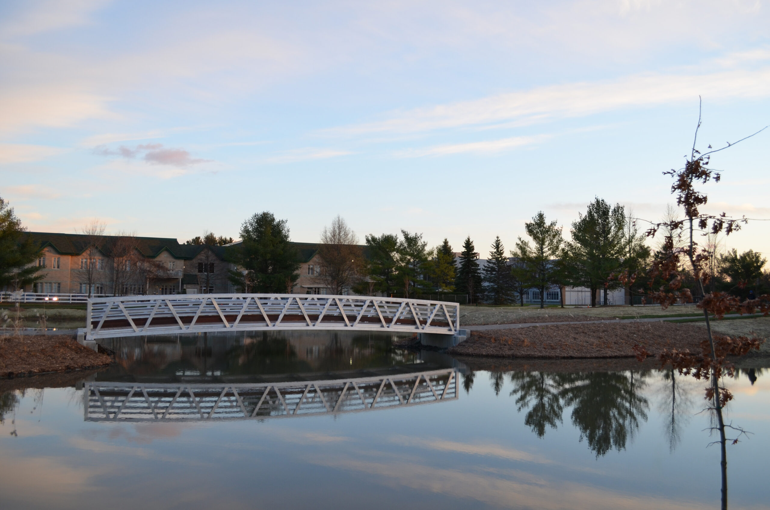 Custom aluminum pedestrian bridge with hardwood decking over pond in Canada