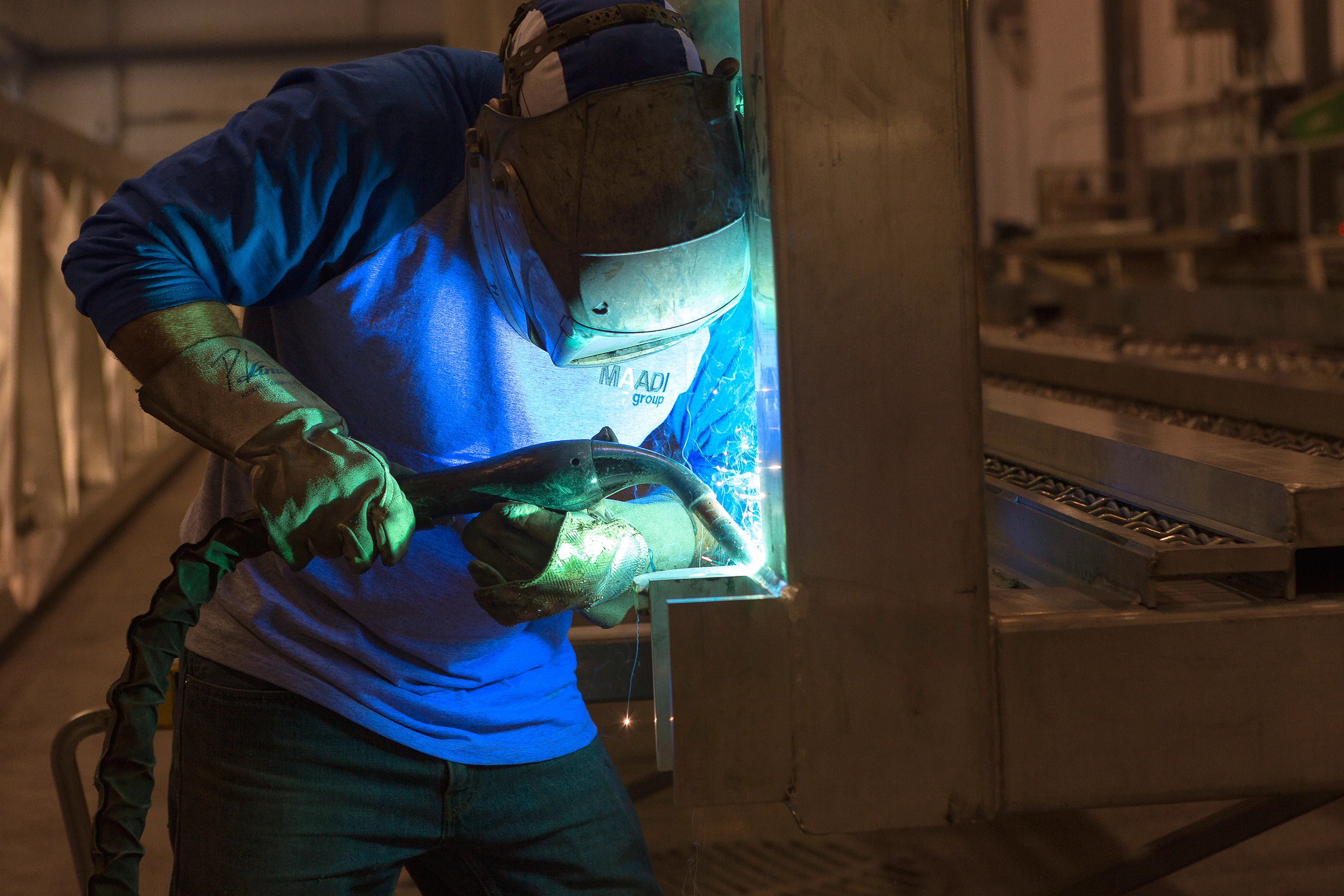 Welder working on aluminum pedestrian bridge at MAADI Group’s new Boucherville bridge manufacturing facility.