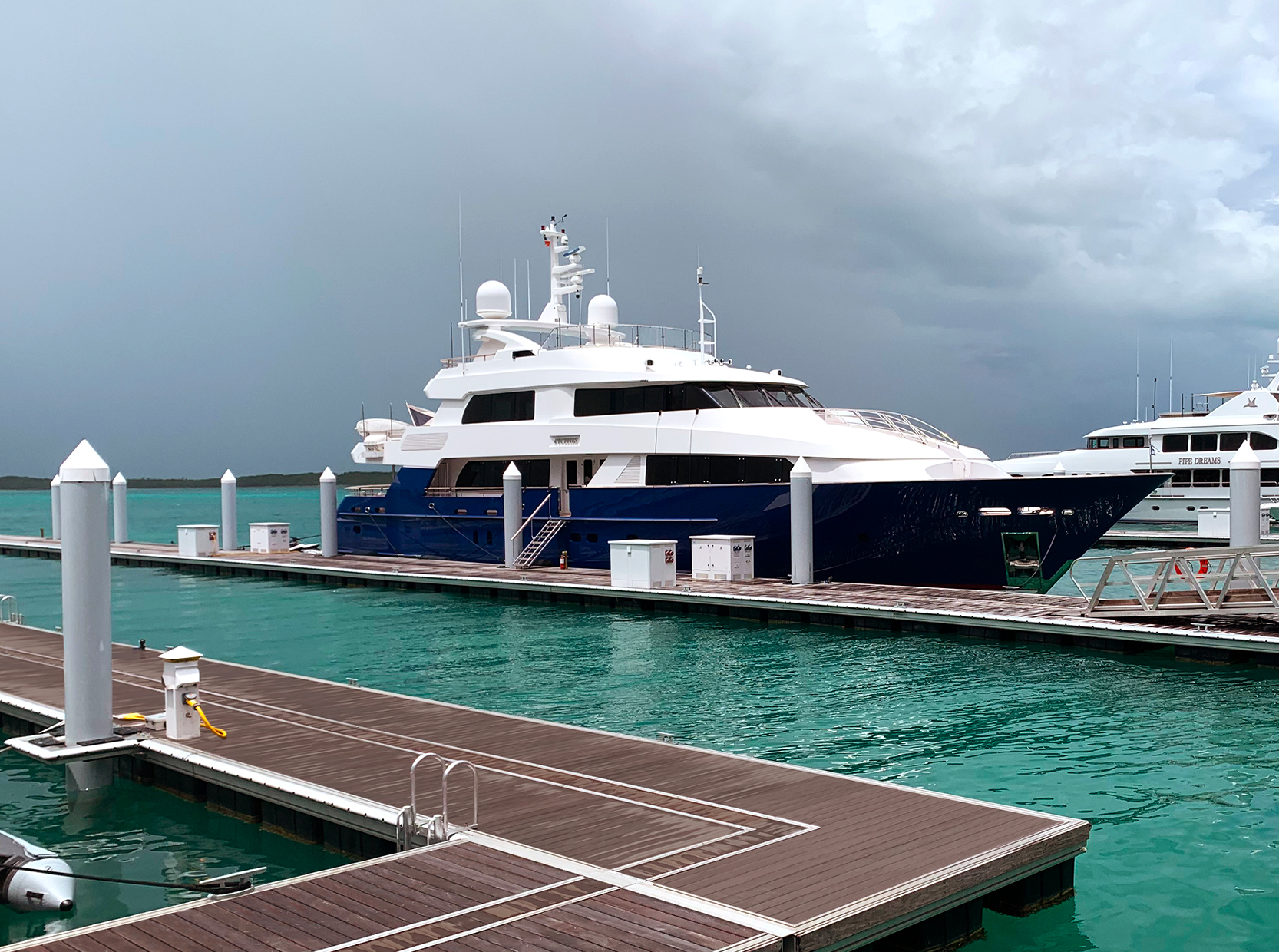 Aluminum docks with wood decking and medium-size yacht moored in the Bahamas
