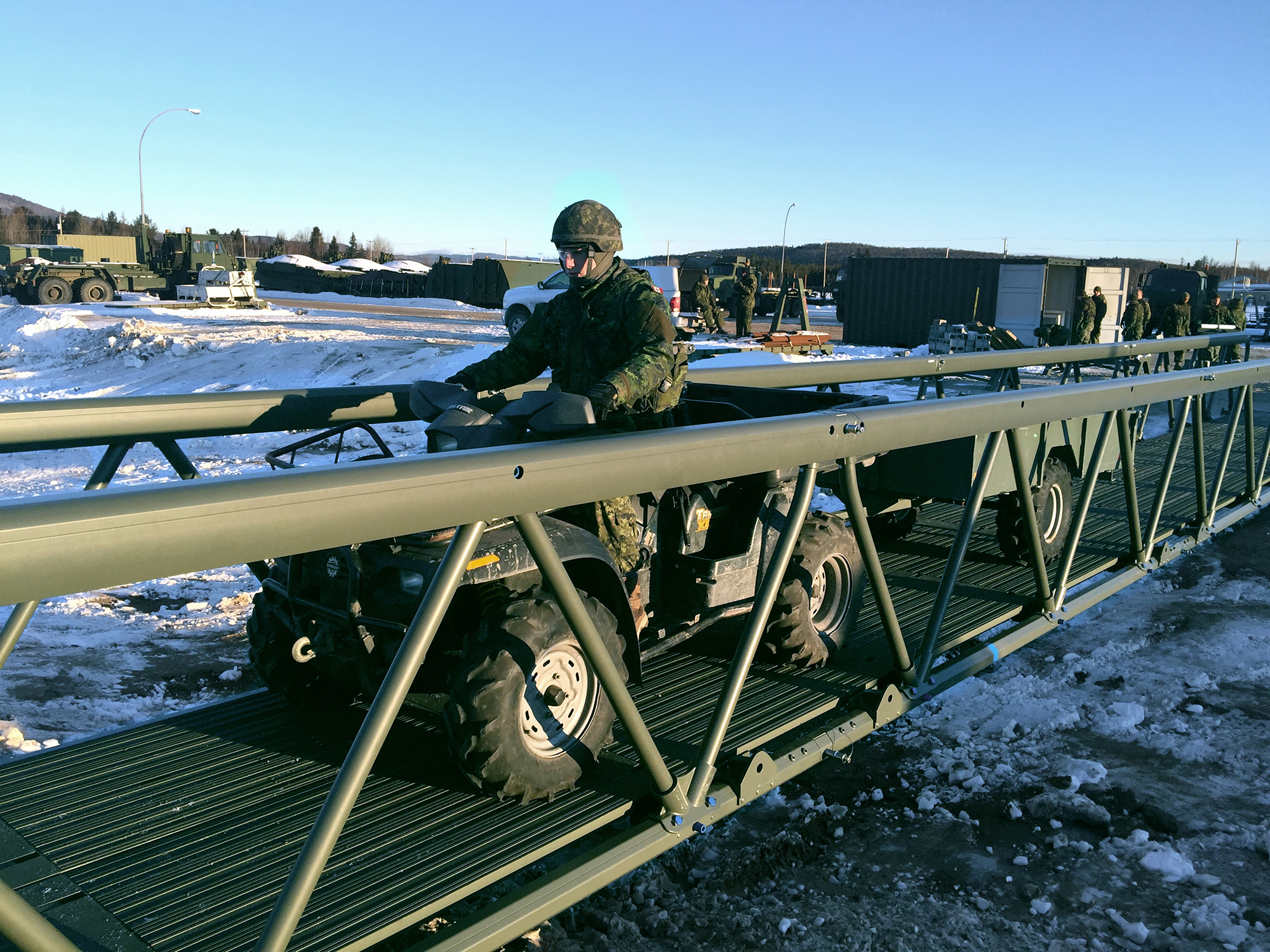 Military ATV driving over lightweight aluminum bridge in cold weather conditions