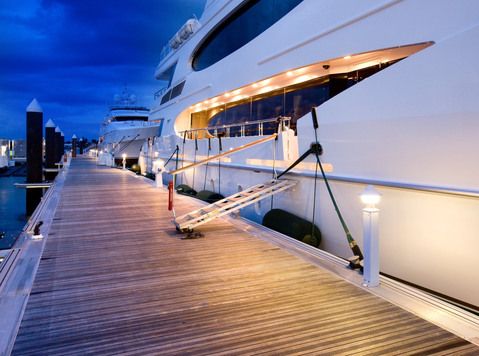 Aluminum floating dock with wood decking and large yachts moored
