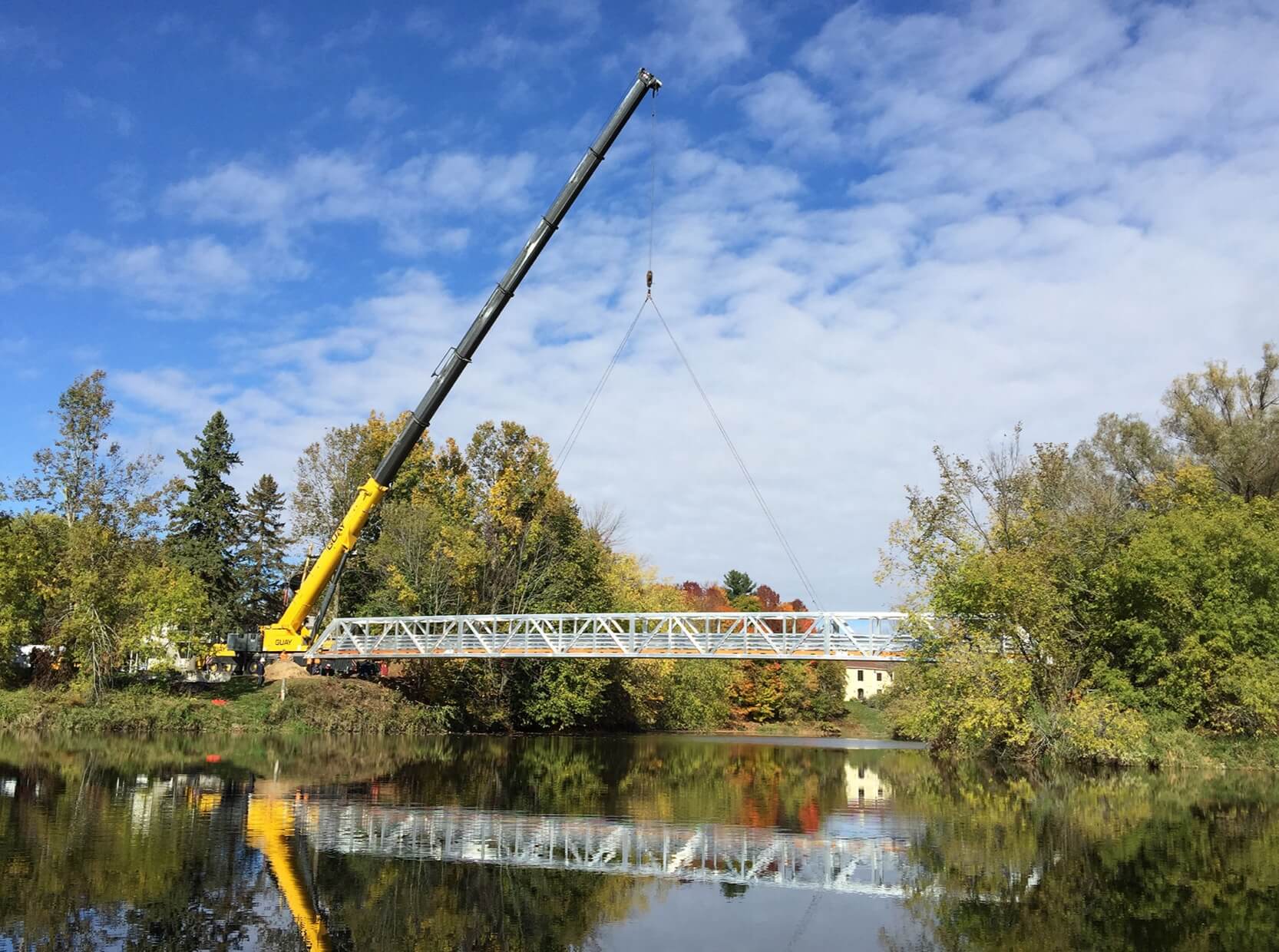Crane lowering an aluminum footbridge into place
