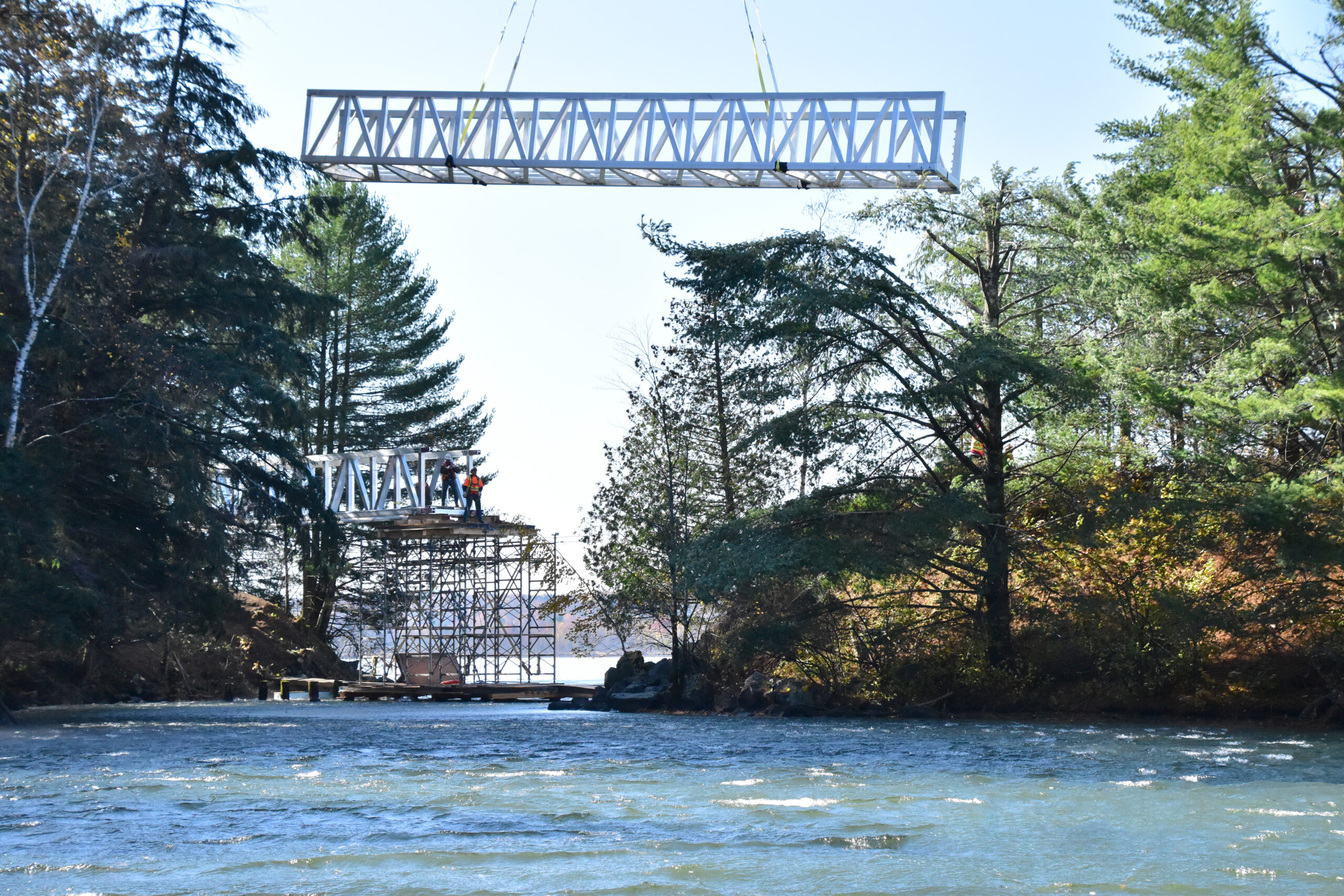 Custom pedestrian bridge being lowered into place over lake in Canada