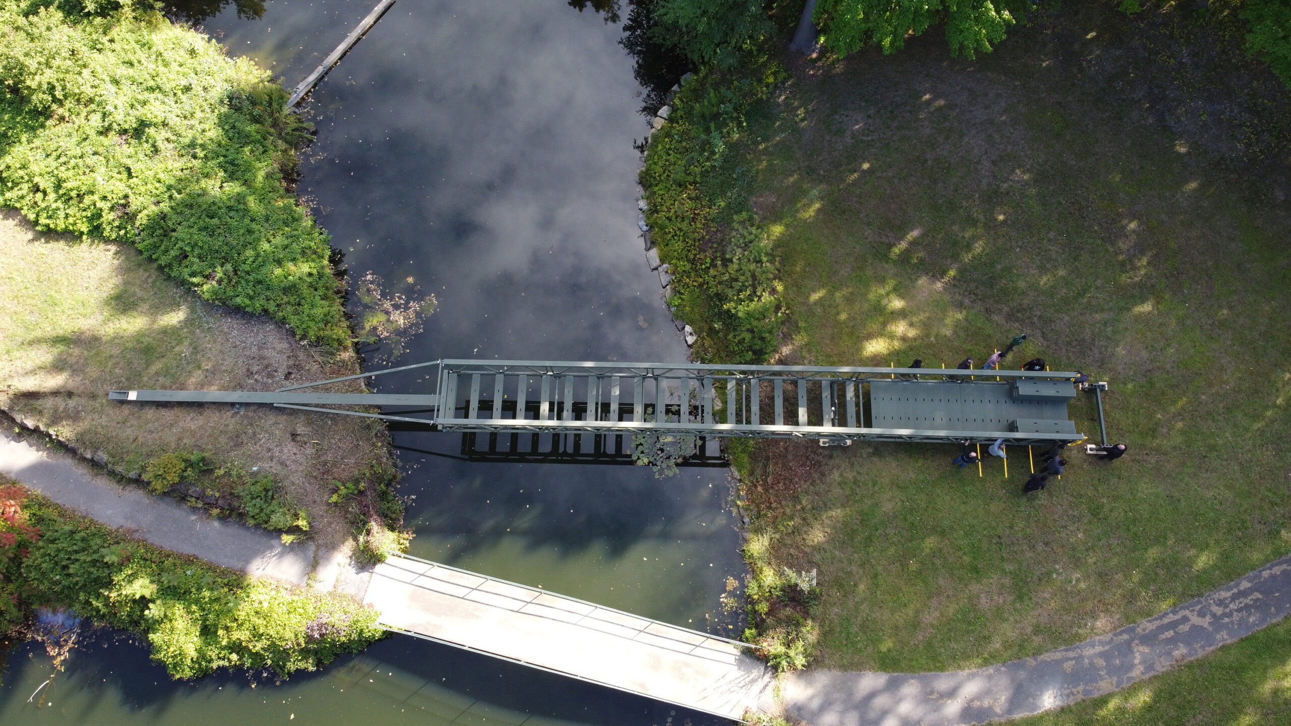 5 people launching modular tactical bridge horizontally across a river