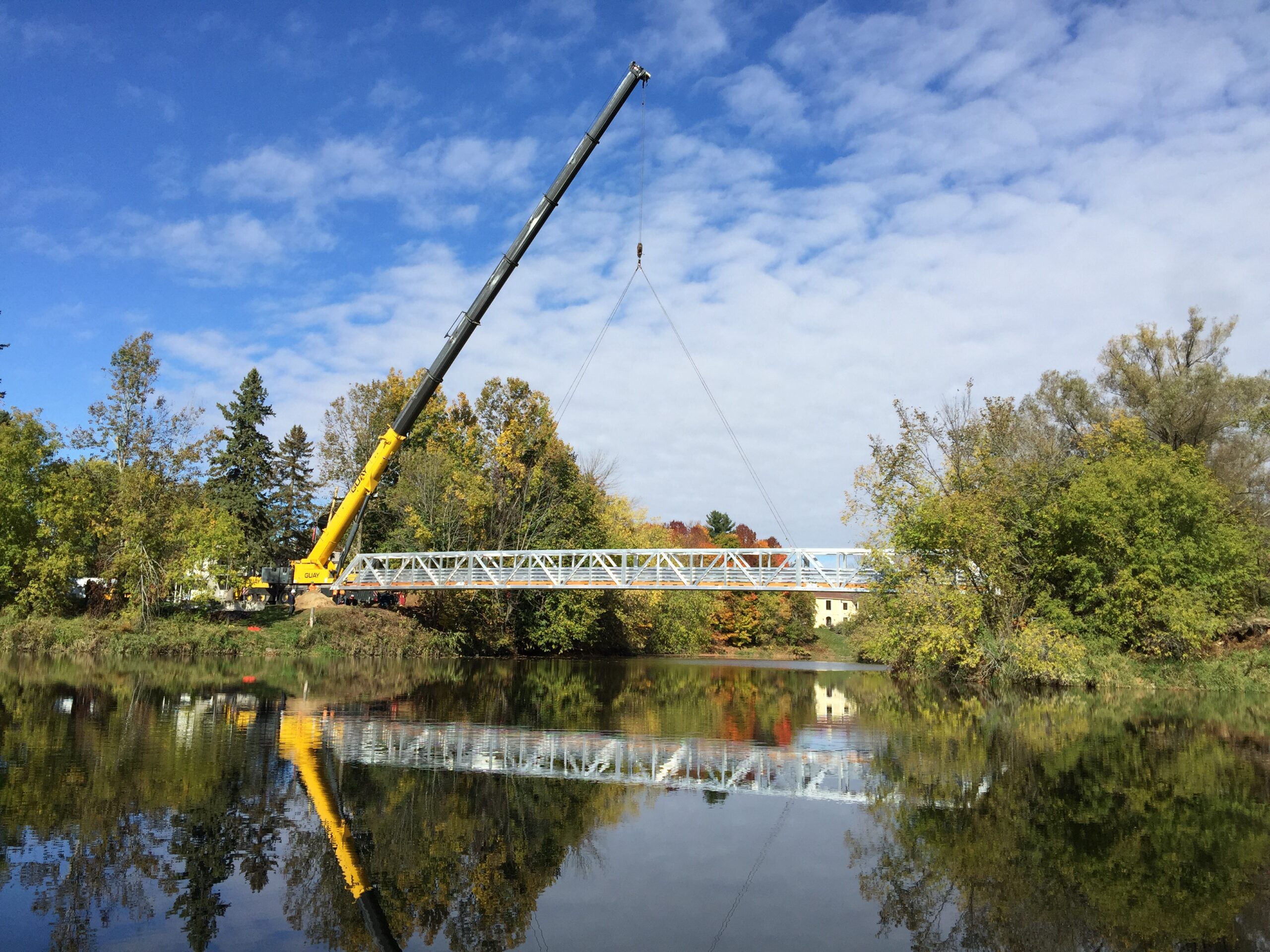 Prefabricated aluminum footbridge being lowered into place by crane
