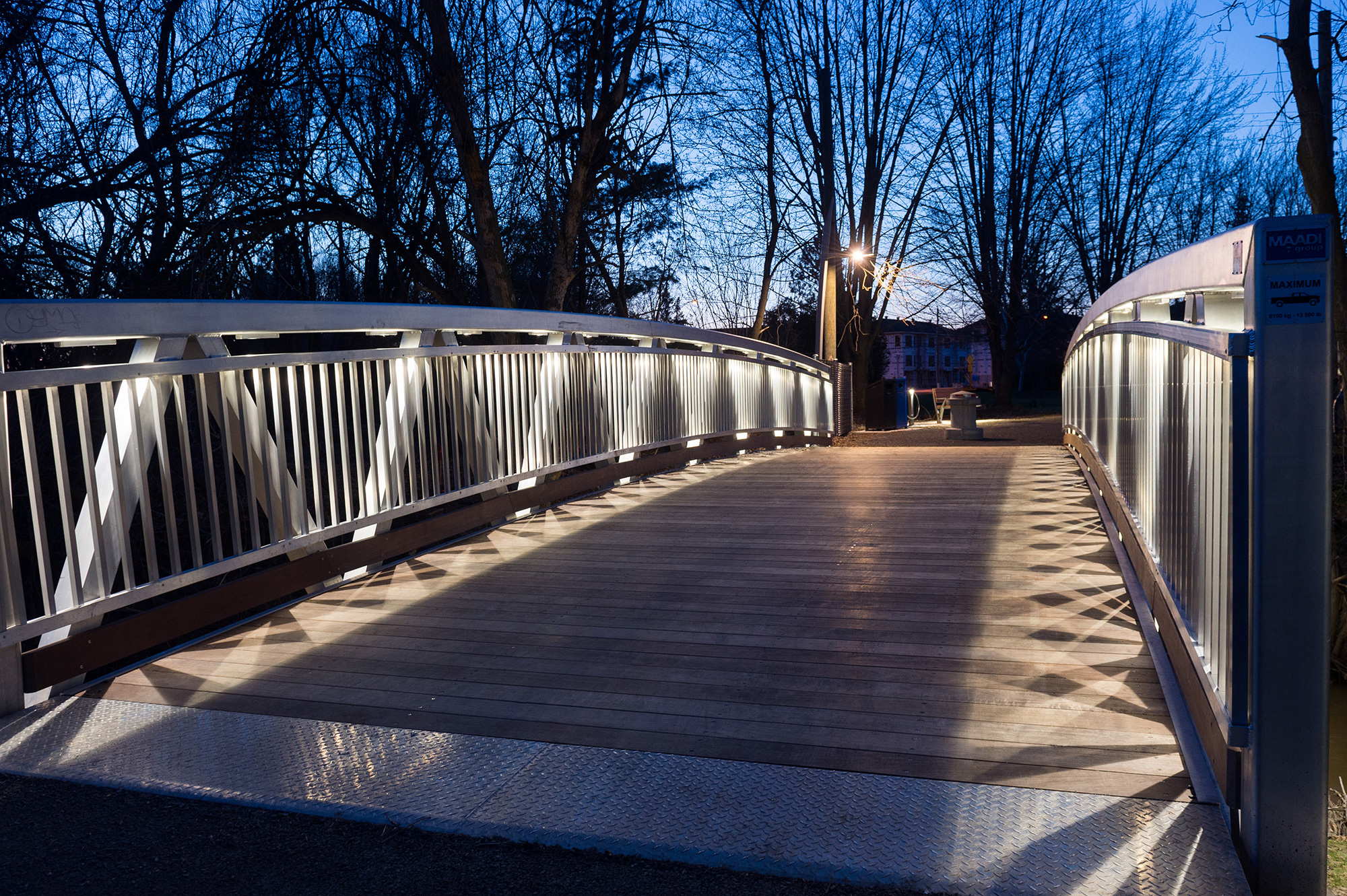 Custom aluminum pedestrian bridge with hardwood decking and built-in LED lighting in Quebec, Canada