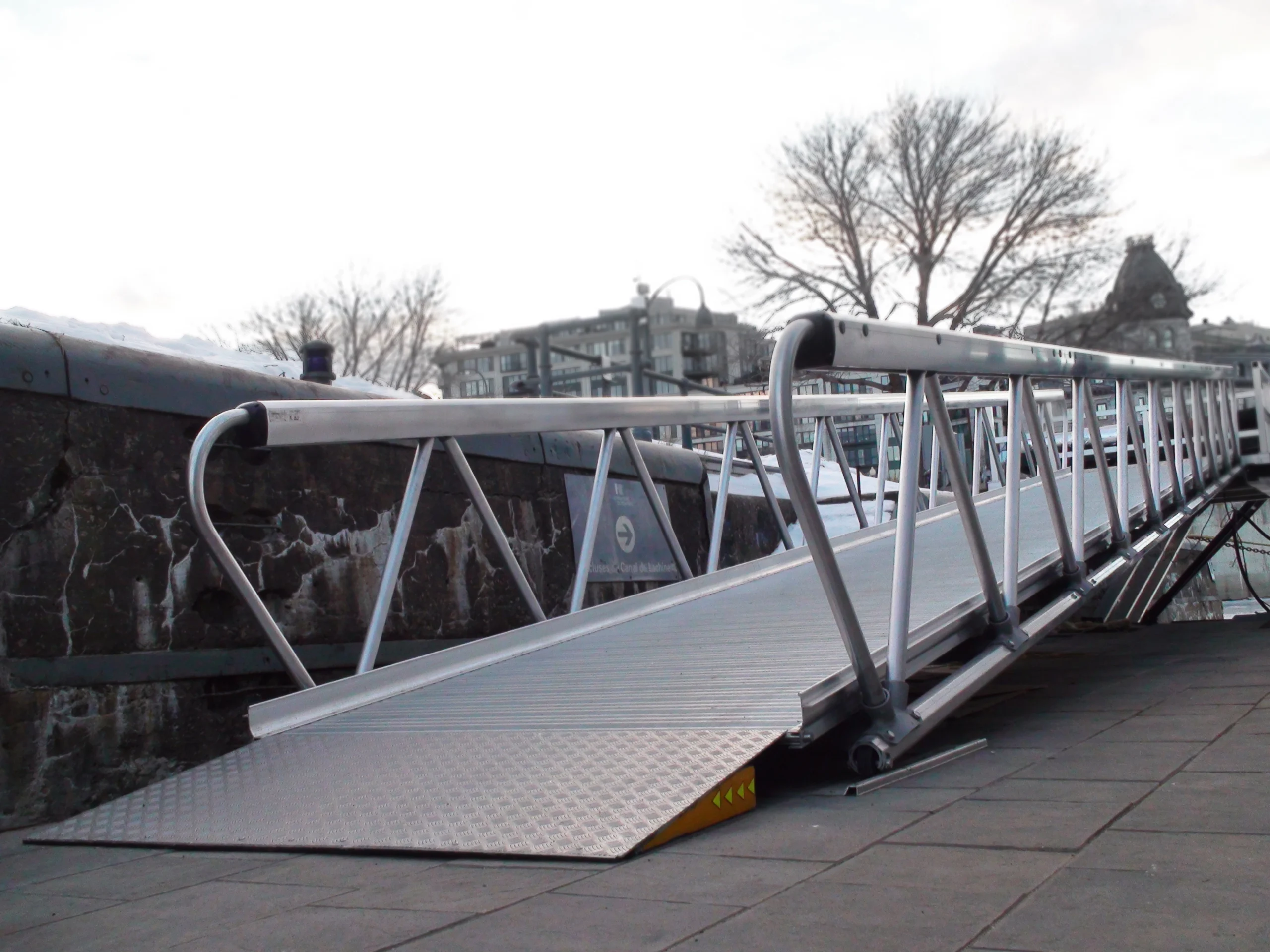 Side view of a 45-foot MakeABridge® aluminum pedestrian bridge at Bota Bota Spa in Montreal, showcasing sleek modular design and waterfront integration.